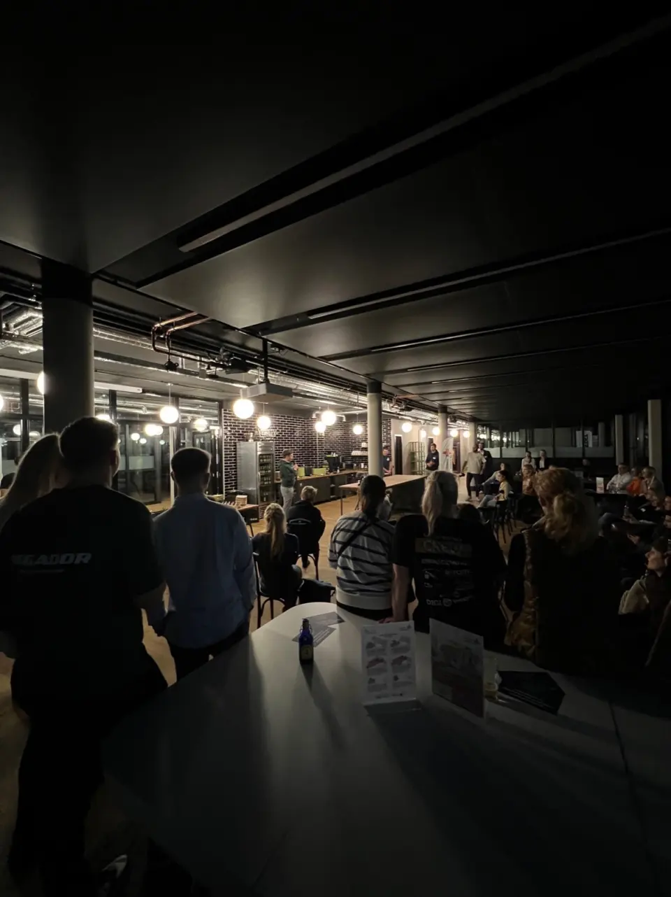 Blick über Köpfe des Publikums auf eine Gesprächsrunde in einem Loft-Raum
